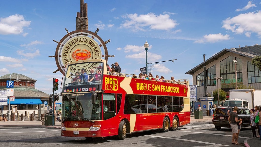 Big Bus San Francisco tour at Fisherman's Wharf with passengers on the open-top deck.