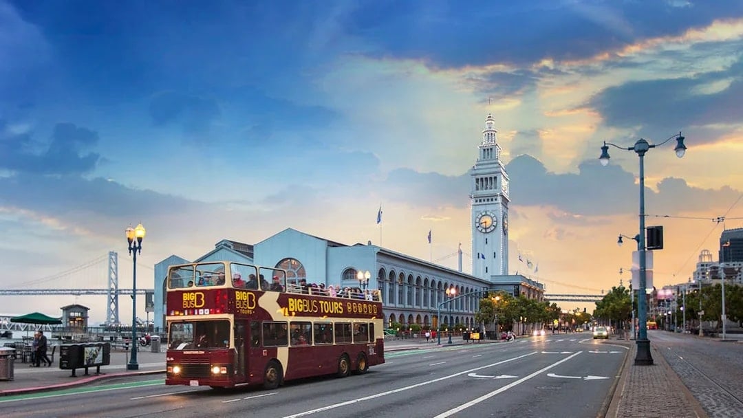 Big Bus passing San Francisco Ferry Building during sunset tour.