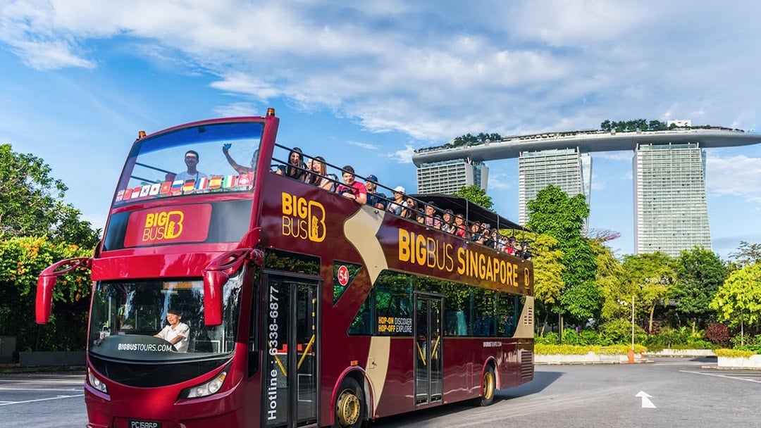 Tourists on a Singapore Hop-On-Hop-Off bus with Marina Bay Sands in the background.