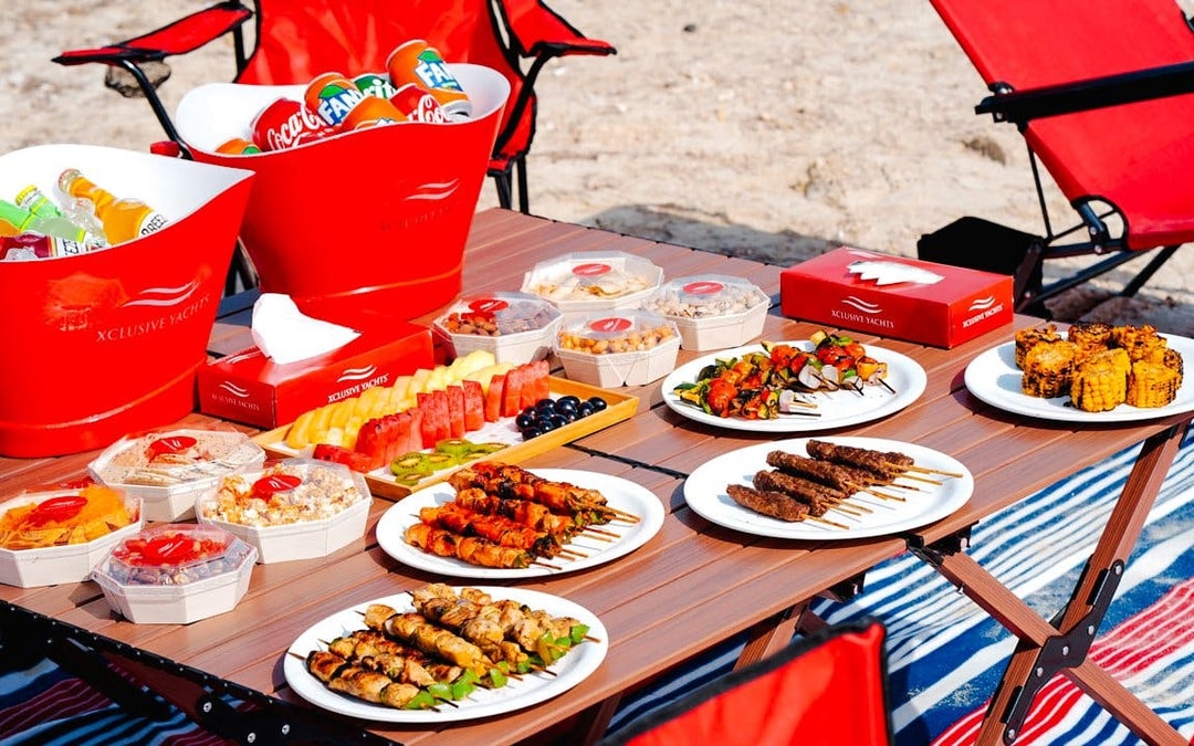 Luxury yacht cruise meal with skewers, grilled corn, fresh fruit, and drinks in Dubai.