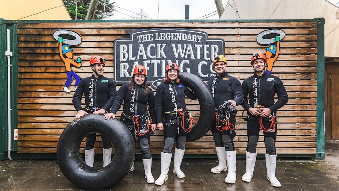 Group of people in wetsuits with inner tubes at Black Water Rafting, Waitomo.