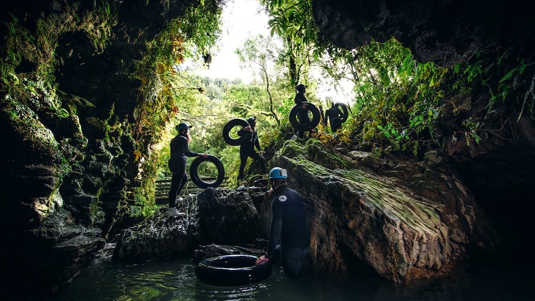 Adventurers with tubes exploring a cave during a black water rafting tour in Waitomo.