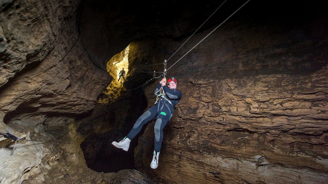 Person ziplining through a cave during a Black Water Rafting experience in Waitomo.