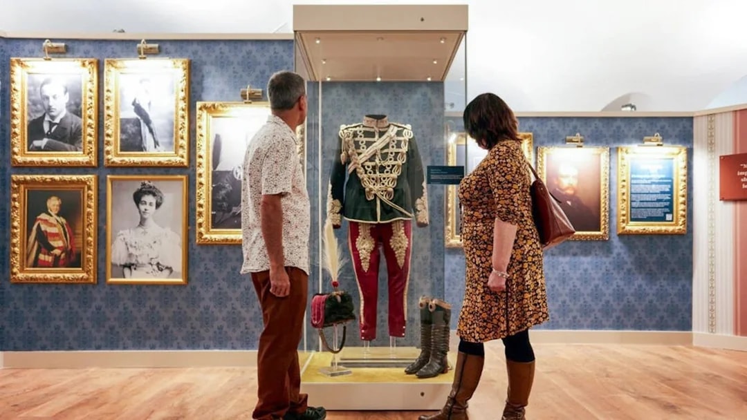 Visitors viewing historical military uniform display at Blenheim Palace State Rooms.