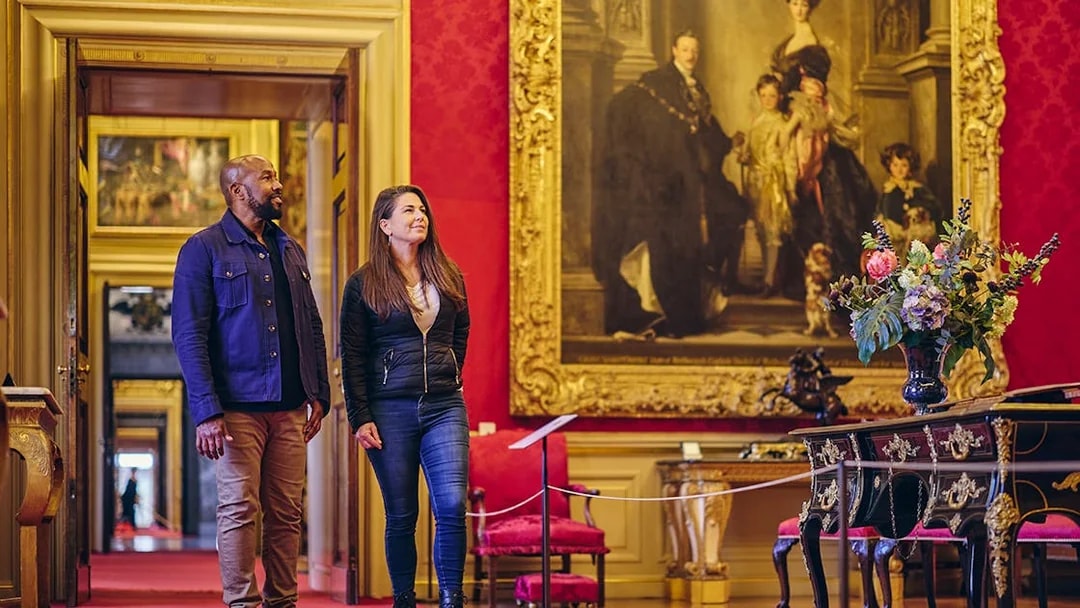 Visitors exploring the ornate State Rooms inside Blenheim Palace, featuring a large historical painting.