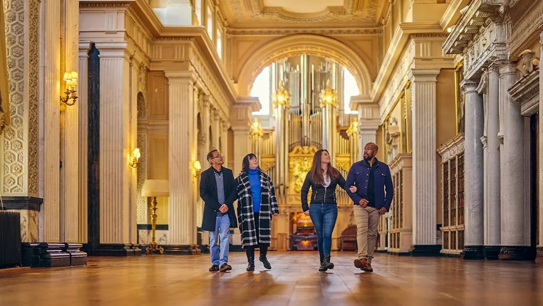 Visitors exploring the ornate Blenheim Palace State Rooms with grand columns and chandeliers.
