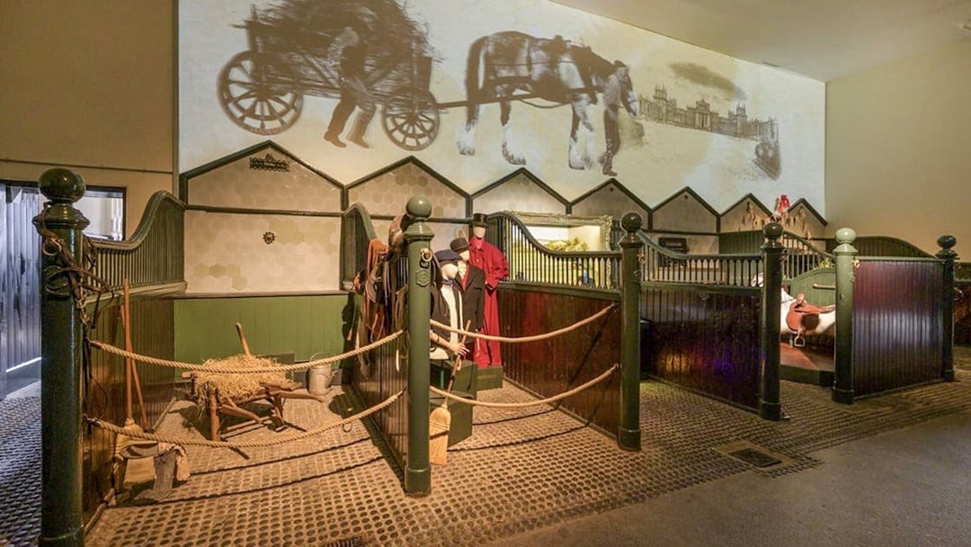 Blenheim Palace State Rooms exhibit with horse stables and historical carriage projection.
