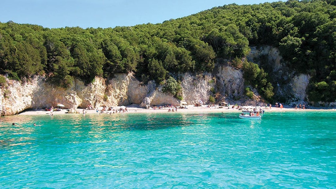 Crystal-clear waters and lush cliffs at Blue Lagoon, Sivota, during Corfu cruise with lunch.