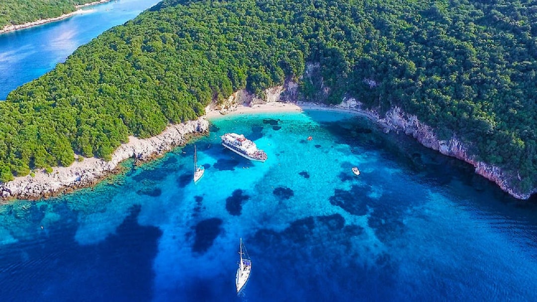 Cruise boats in Blue Lagoon's turquoise waters near Sivota, Corfu, surrounded by lush greenery.