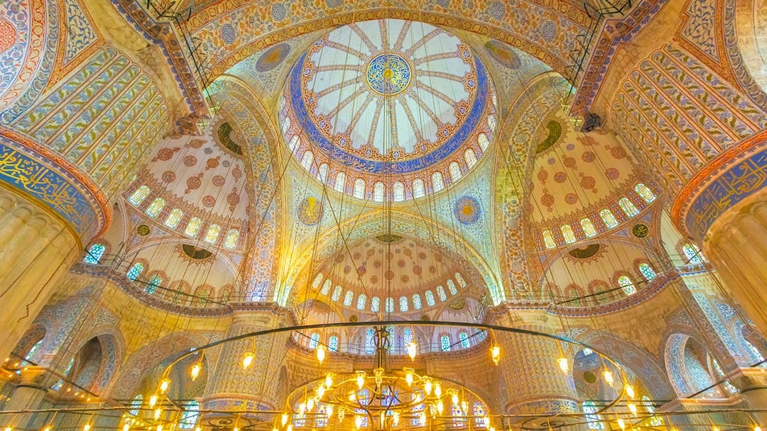 Interior view of the Blue Mosque dome in Istanbul, showcasing intricate patterns and stained glass.
