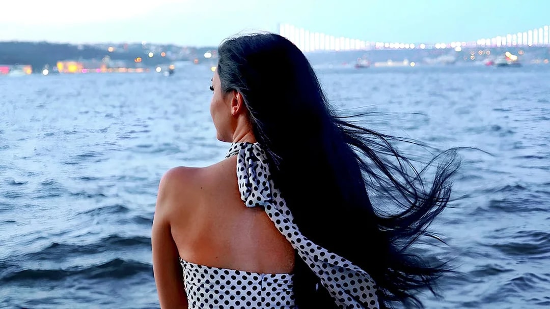 Person enjoying Bosphorus cruise with Istanbul skyline in the background.
