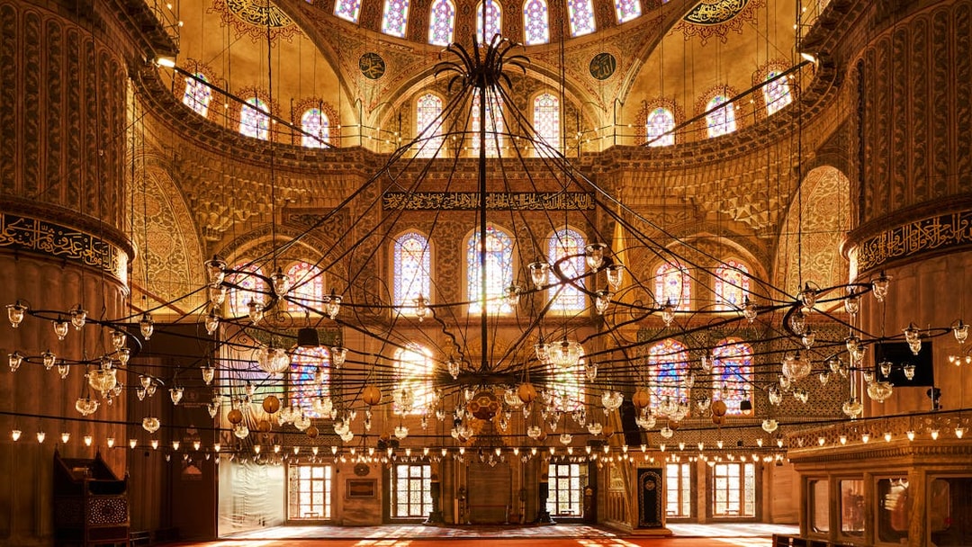 Interior view of Blue Mosque with ornate chandeliers and stained glass windows, Istanbul, Turkey.