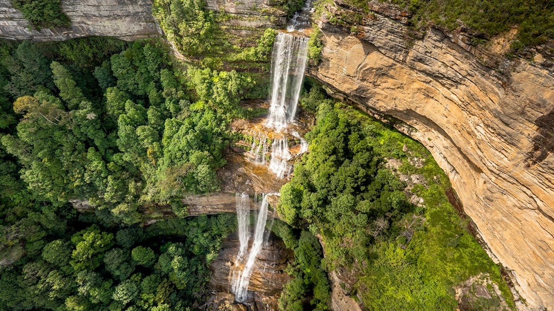 Aerial view of Katoomba Falls cascading through lush green forest, Blue Mountains, Australia.