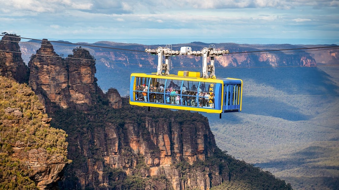 Scenic cable car over Blue Mountains with view of Three Sisters rock formation.