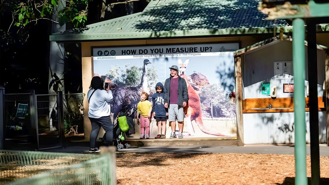 Visitors posing for a photo at Featherdale Wildlife Park's height chart display.