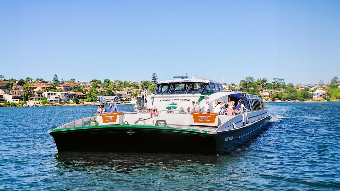 Ferry on Sydney Harbour with passengers, cityscape in background, part of Blue Mountains tour.