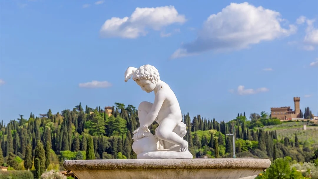 Sculpture in Boboli Gardens with lush greenery and historic architecture, Florence, Italy.