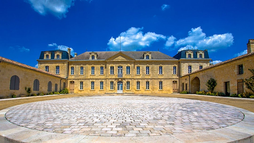 Saint Emilion winery courtyard with historic building under blue sky.