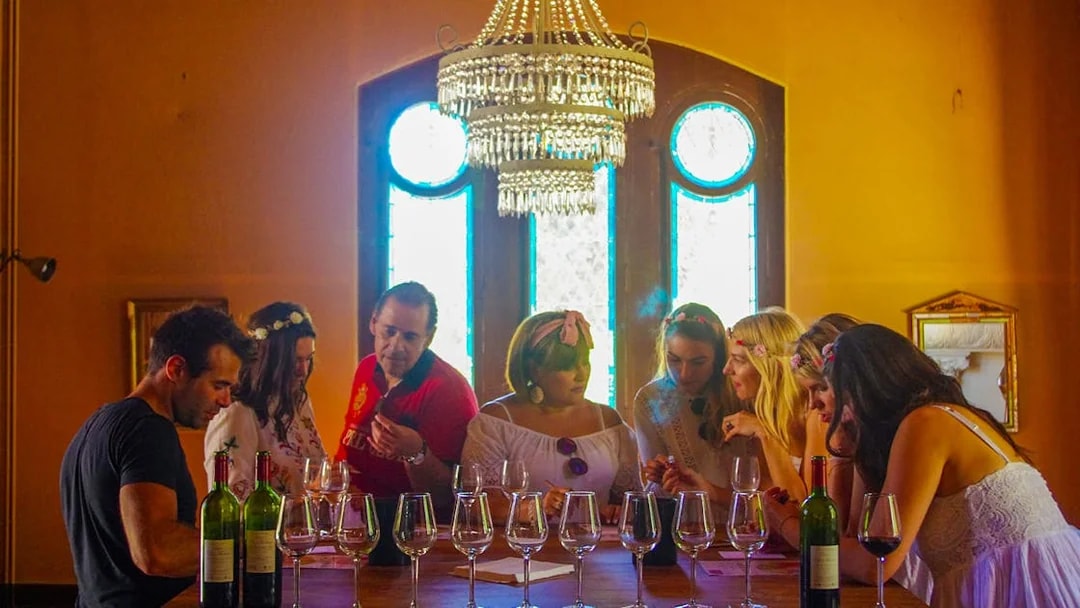 Group wine tasting at a Saint Emilion winery with chandelier and stained glass windows.