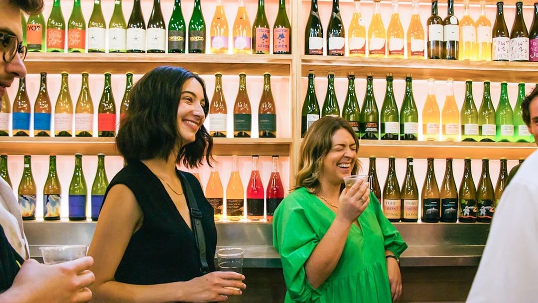 Visitors enjoying drinks at a wine stall in Borough Market, London.