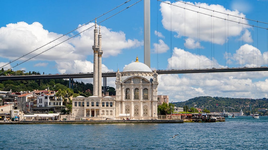 Ortaky Mosque with white stone architecture and twin minarets by the Bosphorus Bridge, Istanbul.