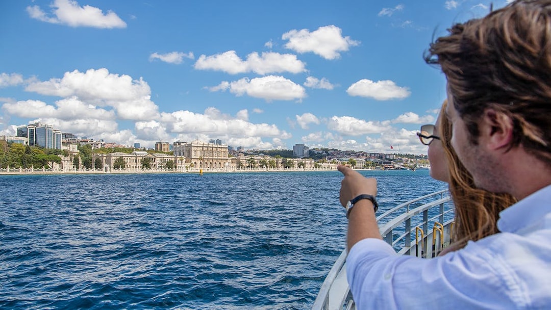 Couple on Bosphorus cruise pointing at Dolmabahçe Palace, Istanbul.