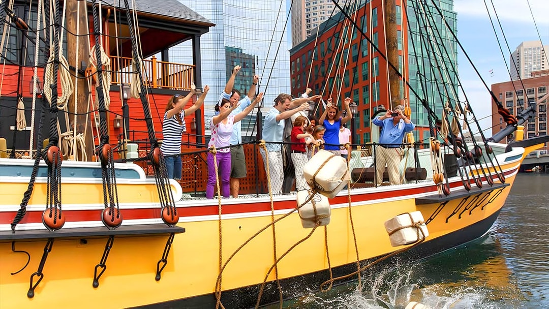 Tourists reenacting the Boston Tea Party by throwing tea chests from a ship in Boston Harbor.