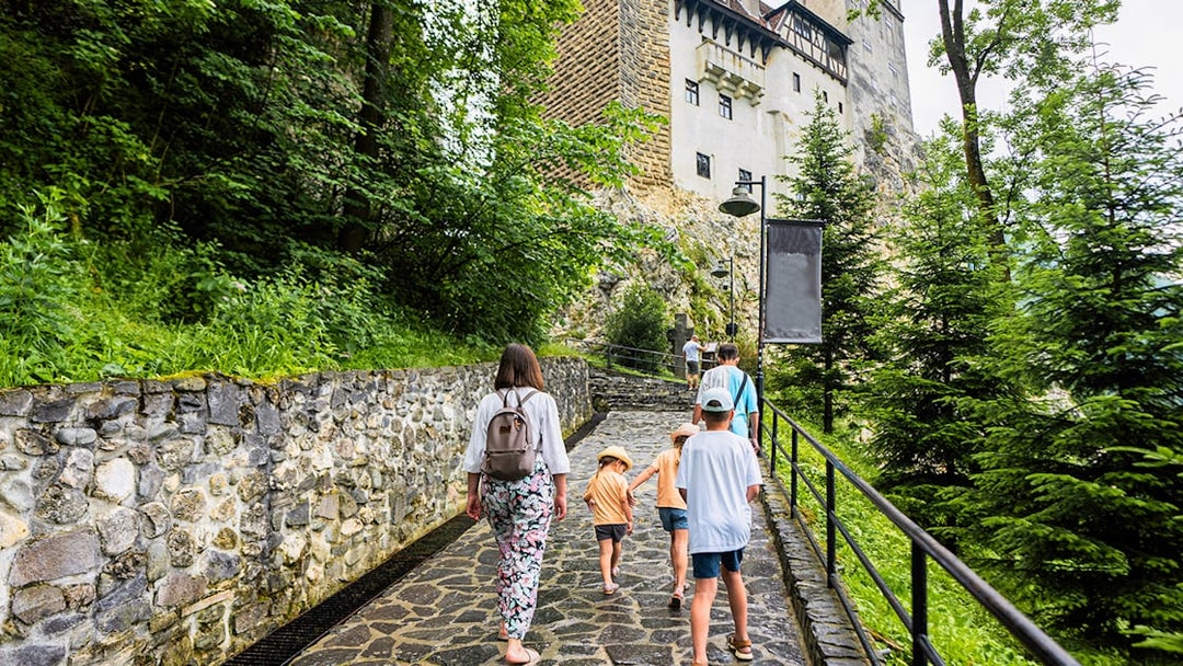 Family walking on path towards Bran Castle, Romania.