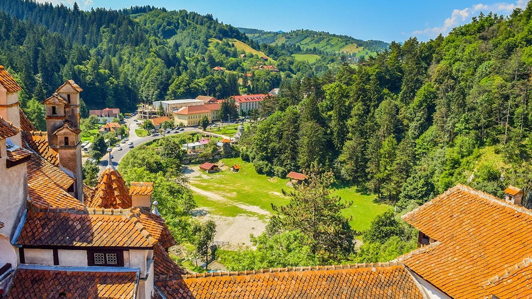Bran Castle view of Romania cityscape with forested hills and village.