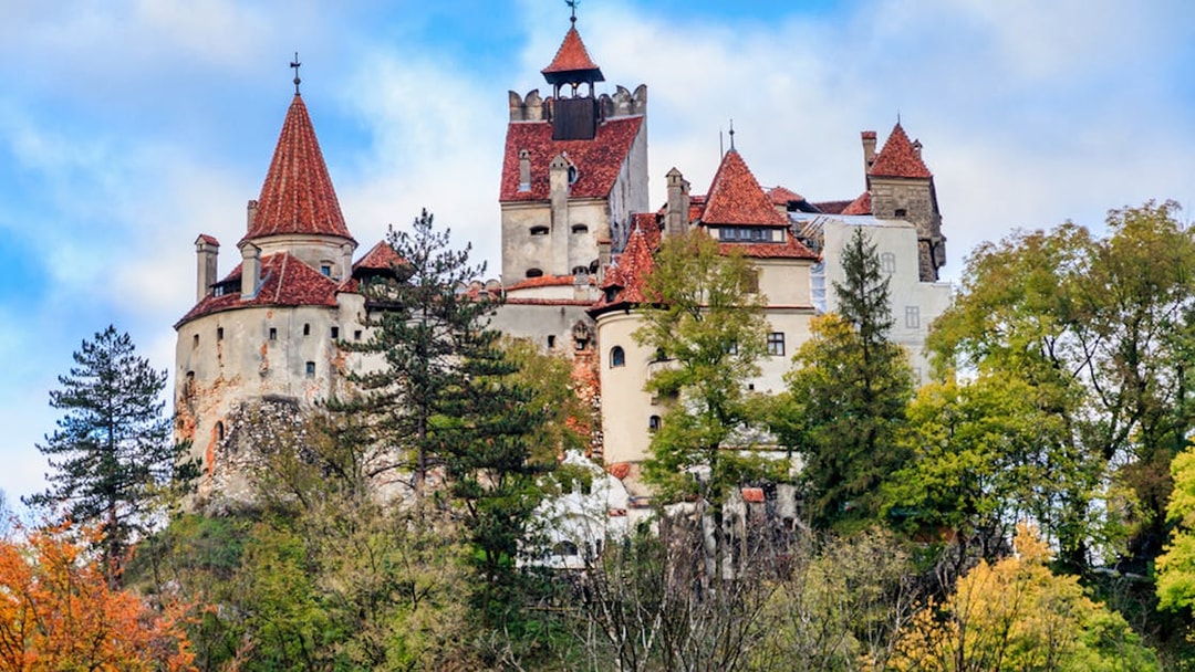 Bran Castle surrounded by autumn trees, part of a guided tour in Romania.