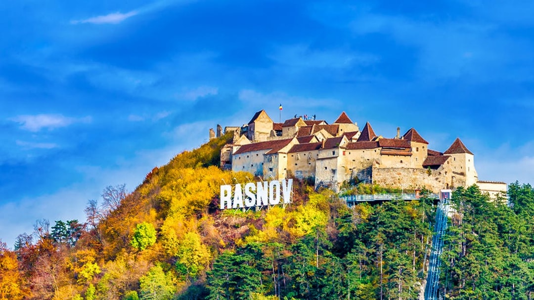 Rasnov Fortress on a hill with autumn foliage, Romania.