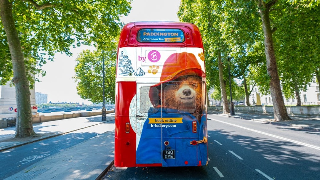 Red double-decker bus with Paddington Bear design for Brigit's Bakery Afternoon Tea tour in London.