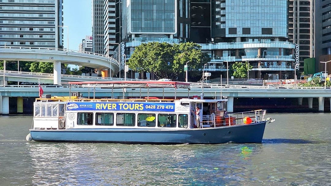 Boat cruising on Brisbane River with city buildings in the background.