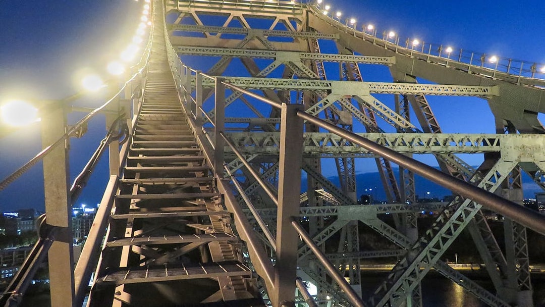 Climbing stairs on Brisbane Story Bridge at twilight.