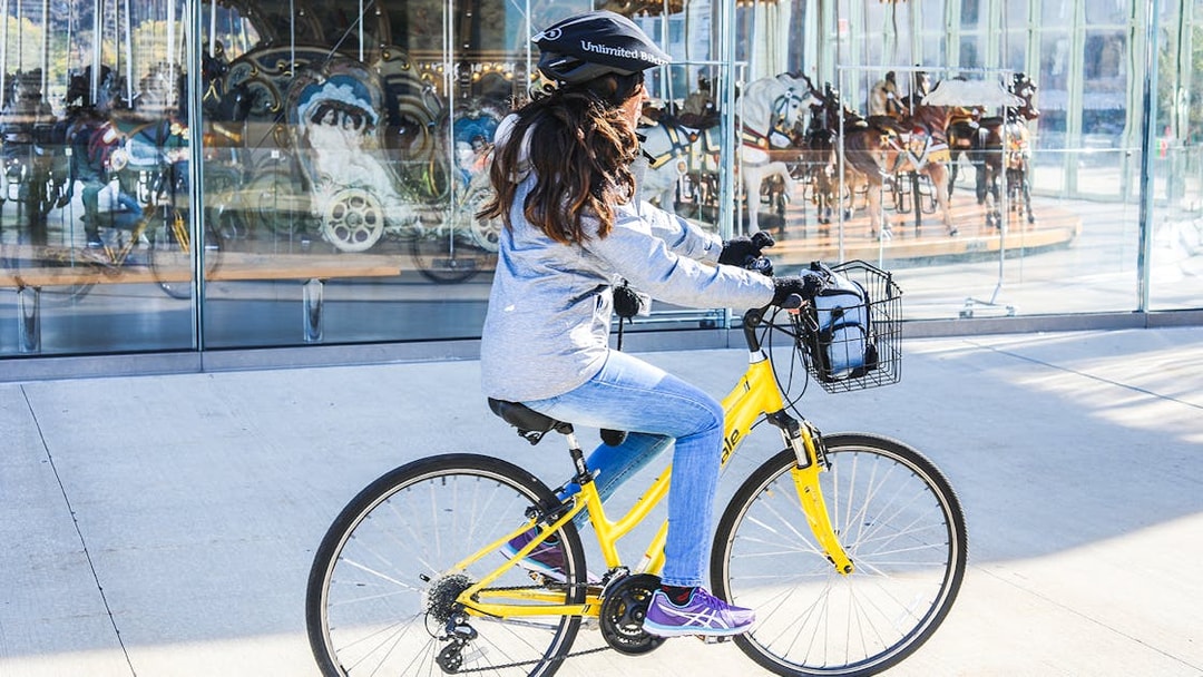 Person riding a yellow bike near Jane's Carousel in Brooklyn.