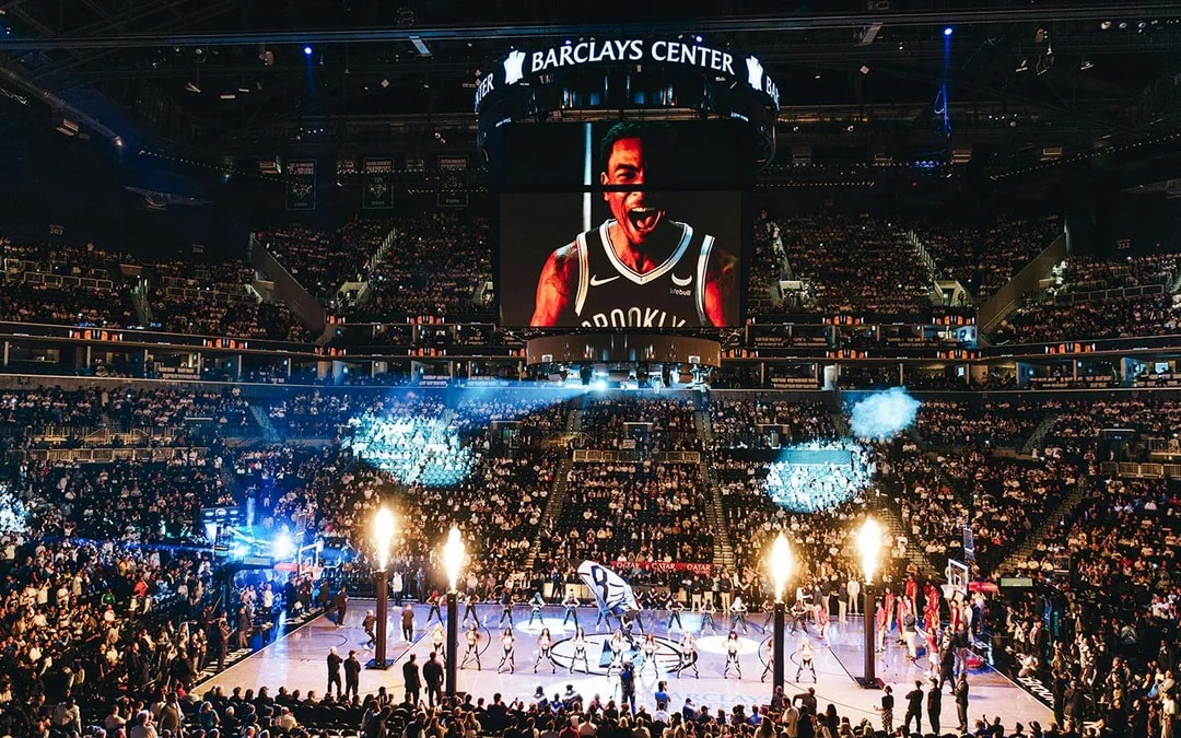 Barclays Center packed for Brooklyn Nets game with large screen and cheering crowd.
