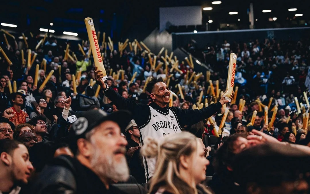 Crowd cheering at a Brooklyn Nets game with foam sticks.