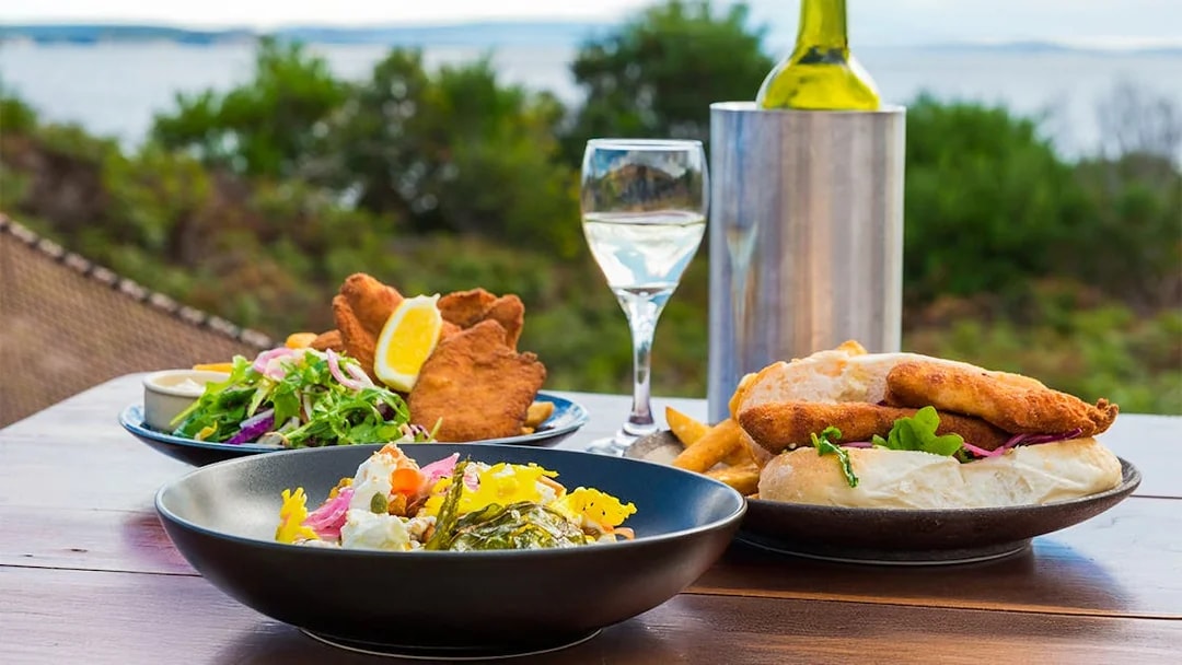 Outdoor dining with seafood and salad on Bruny Island, overlooking the coastline.