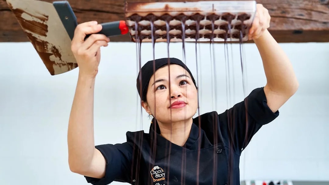 Chocolatier pouring chocolate into molds at Choco Story Brussels.
