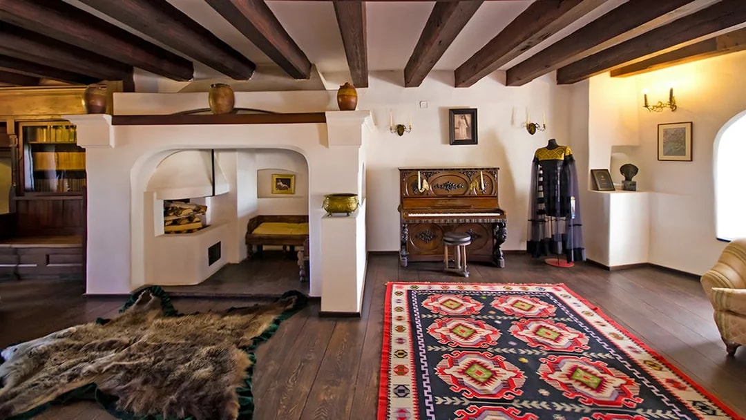 Bran Castle hall with medieval furniture, stone walls, and a colorful rug in Transylvania, Romania.