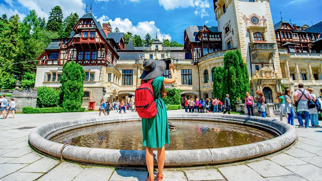 Tourist photographing Peleș Castle courtyard in Sinaia, Romania.
