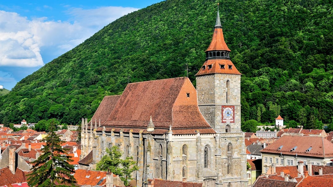Black Church in Brașov with forested hill backdrop.