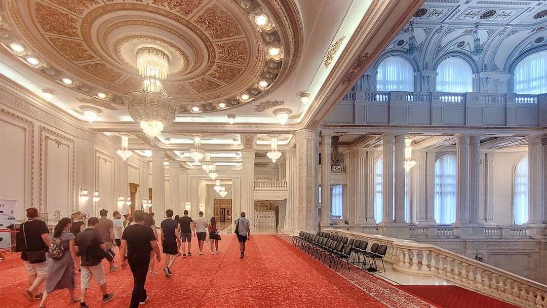 Visitors walking through ornate hall in Palace of Parliament Bucharest.