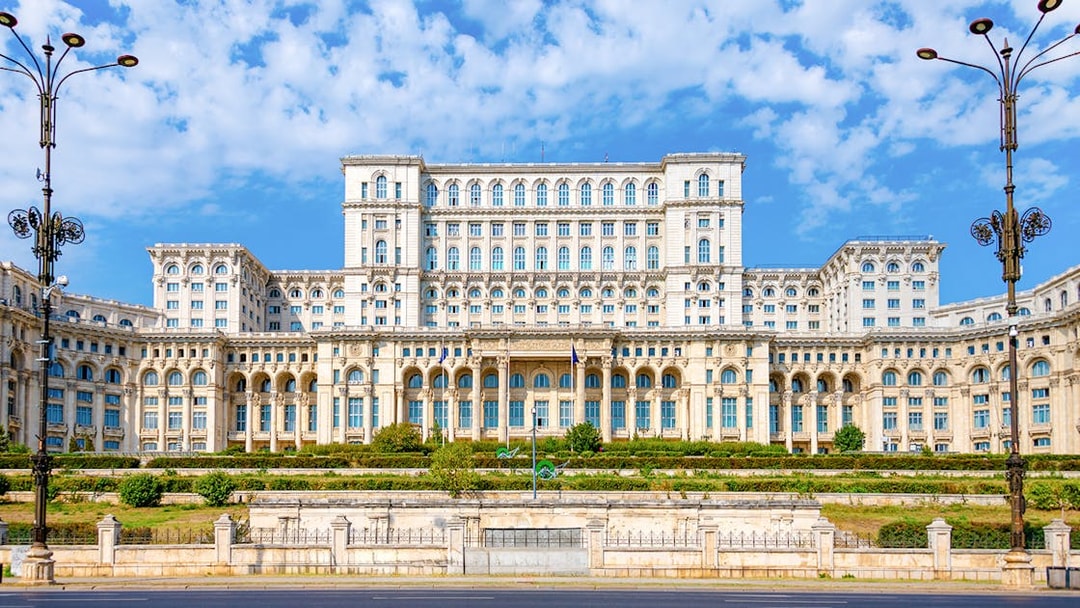 Palace of Parliament in Bucharest with ornate facade and clear blue sky.