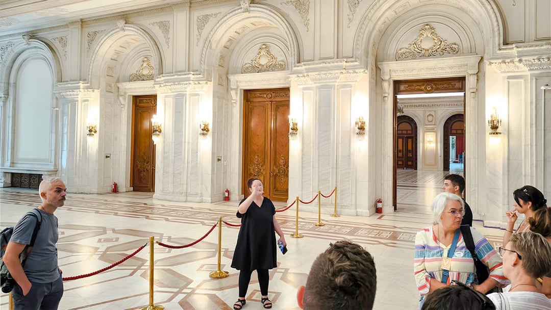 Guide leading a tour inside the ornate interior of the Palace of Parliament.