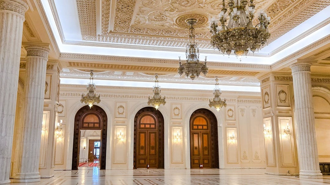 Palace of Parliament interior with ornate chandeliers and marble columns.