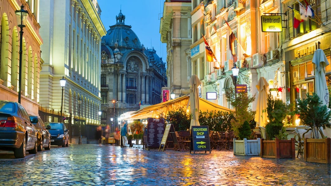 Bucharest street view with historic architecture and outdoor cafes at dusk.