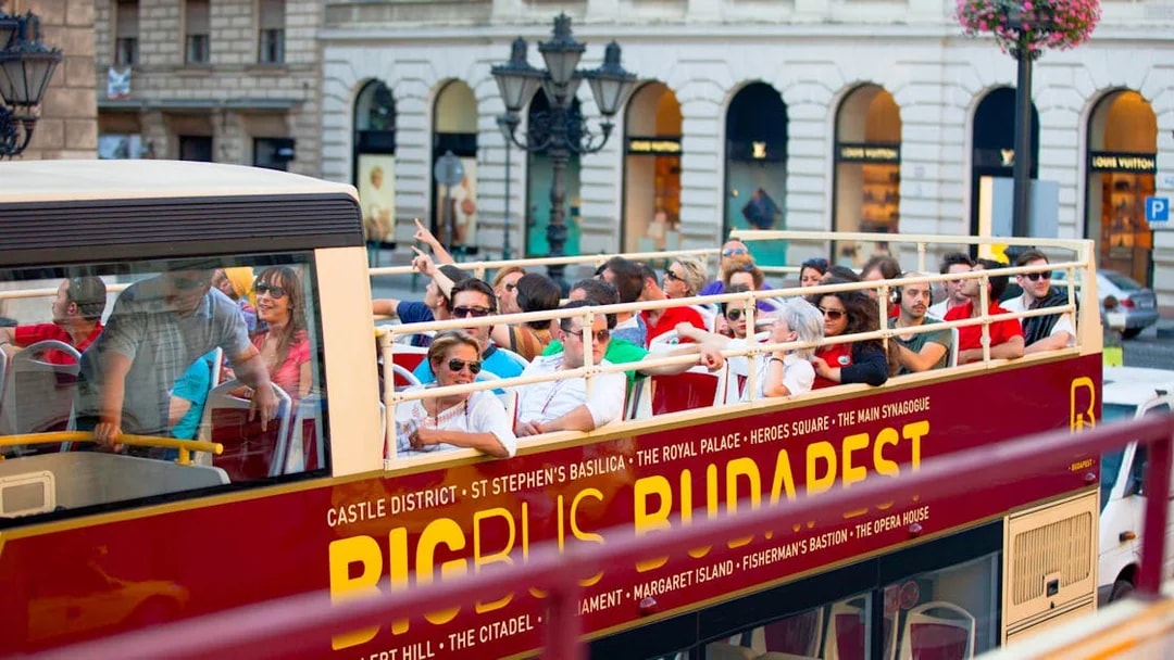 Open-top bus with tourists on a Hop-On Hop-Off tour in Budapest.