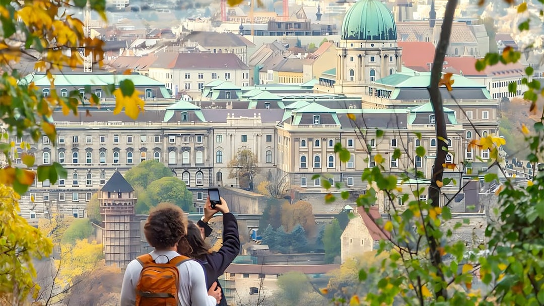 Tourists photographing Buda Castle in Budapest through autumn foliage.
