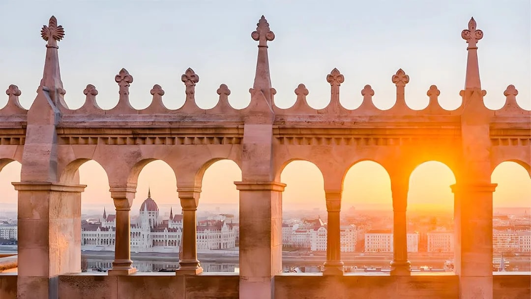 Fisherman's Bastion arches with Budapest Parliament view at sunrise.